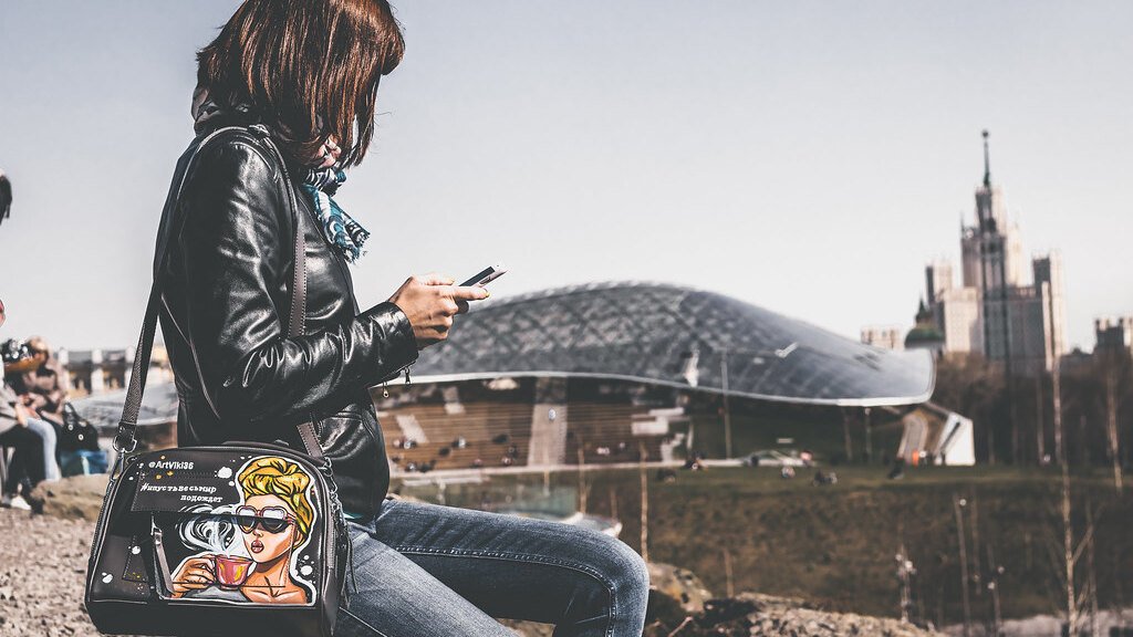 A woman checking social media on her smartphone outdoors